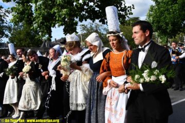 Cornwall Festival, Brittany with ladies in big ats and traditional costumes of long skirts and aprons and men in dark costumes walking in line in street