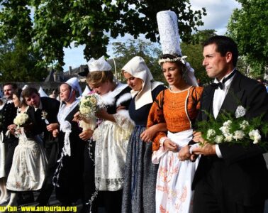 Cornwall Festival, Brittany with ladies in big ats and traditional costumes of long skirts and aprons and men in dark costumes walking in line in street