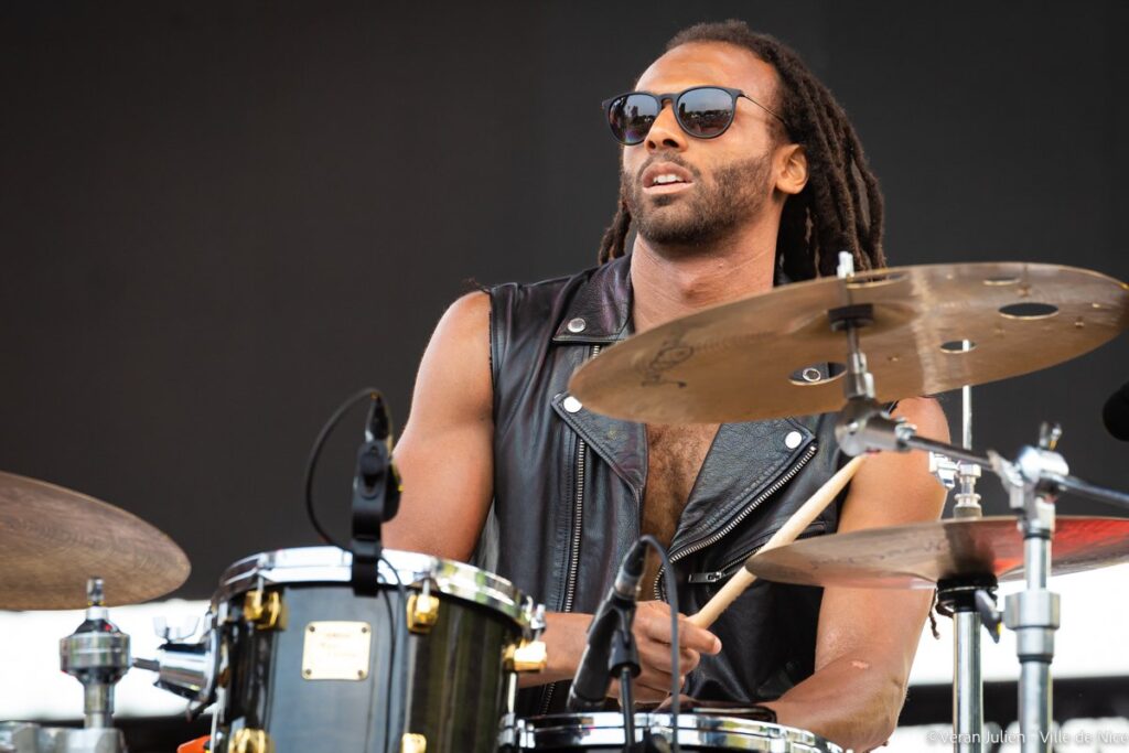 Jazz drummer at Nice Jazz festival wearing just black leather gilet, dark glasses, drumming and looking very cool