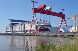 saint nazaire chantiers de l'Atlantique ship yard with huge double gantry cranes moving part along an enormous ship being built