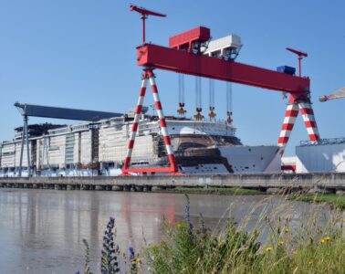 saint nazaire chantiers de l'Atlantique ship yard with huge double gantry cranes moving part along an enormous ship being built