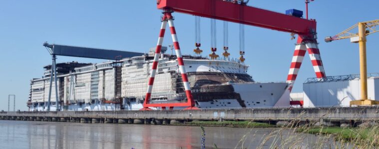saint nazaire chantiers de l'Atlantique ship yard with huge double gantry cranes moving part along an enormous ship being built