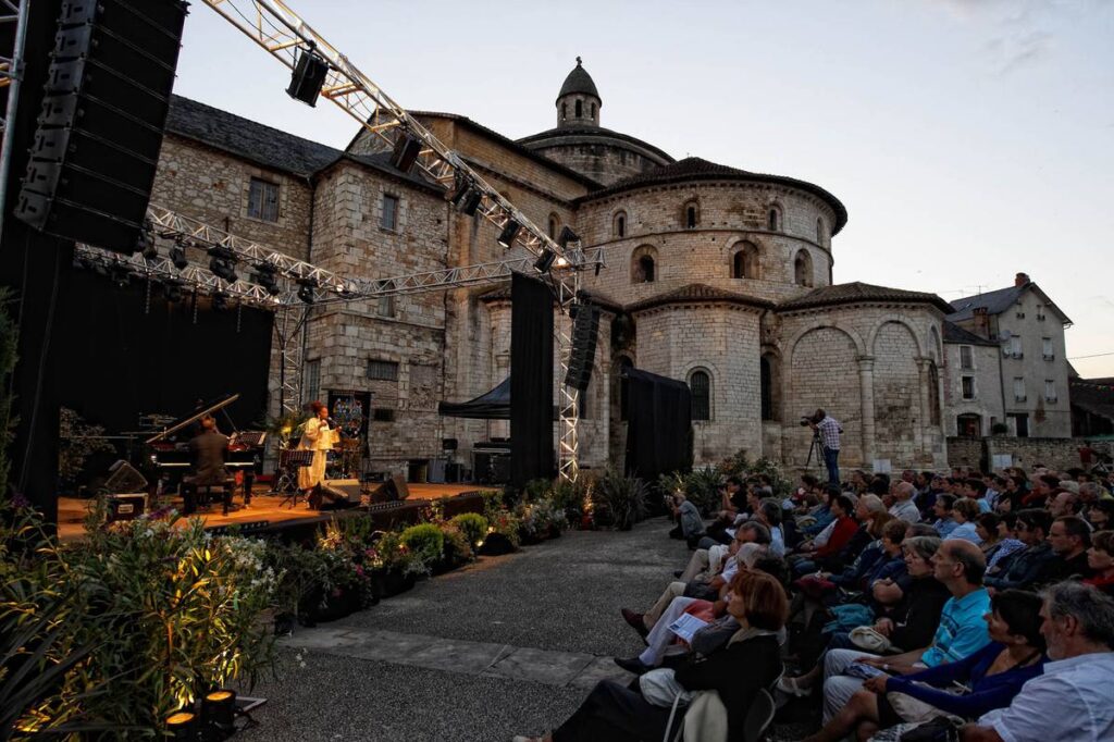 Souillac en jazz festival showing ancient abbey and outdoor stage with performers and audience