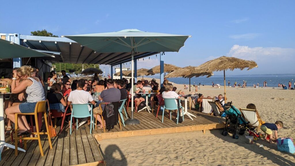 Le Papillon beach bar in saint-nazaire with small covered bar with awnings protecting seating space and beach in front with more tables and chairs