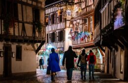 Strasbourg Christmas market fof families with one walking through cobbled street all lit up