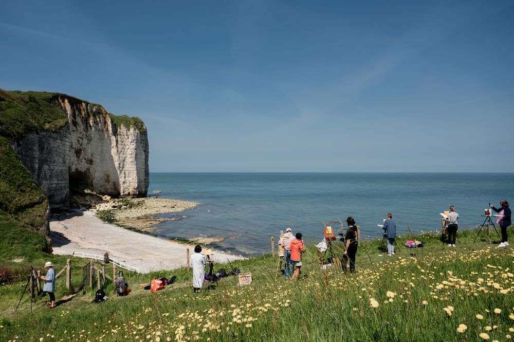 Valleuse de Vaucottes Normandy with people painting on cliff top in field of grass and flowers looking at dramatic cliffs and beaches and sea on the Alabaster Coast