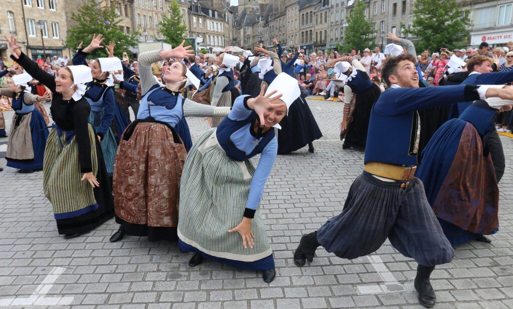 Saint Loup festival with male and female dancers in traditional costume in streets making extravagant gestures and weird poses