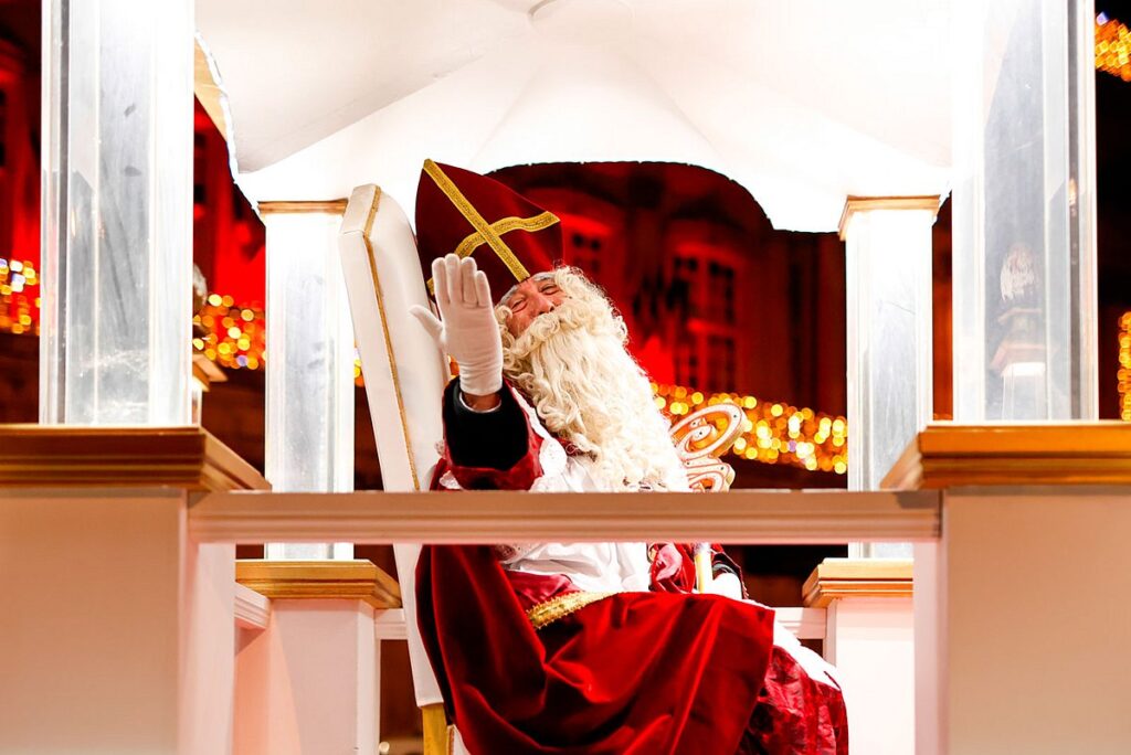 St Nicolas Festival in Nancy with St Nicolas in red robes with crown and huge beard sitting in white canopy