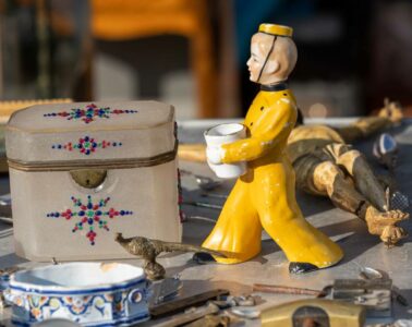 Foire de Chatou showing table of small objects like boy in yellow suit delivering, box, china