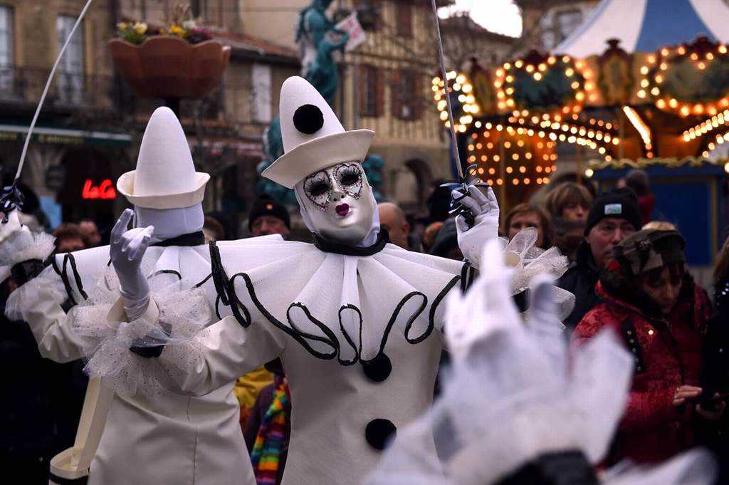 Limoux Carnival with figure in white clown clothese with white hat in busy street