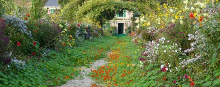 Giverny looking down pergola over path covered in green towards Monet's house in background