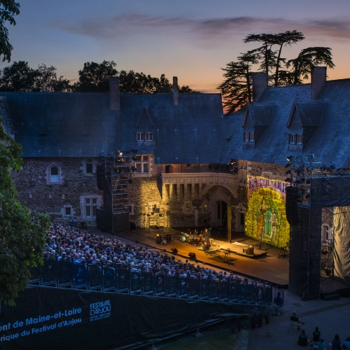 Anjou Festival looking down from high up onto seated audience and old castle with stage at night