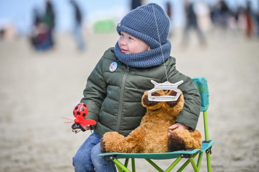 Internatinal kite festival small child well wrapped up with toy on sand
