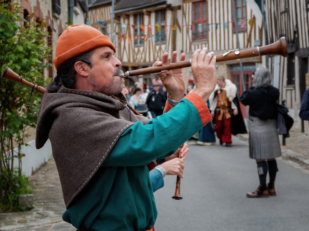 Provins medieval festival with man on horn instrument in street of half timbered houses