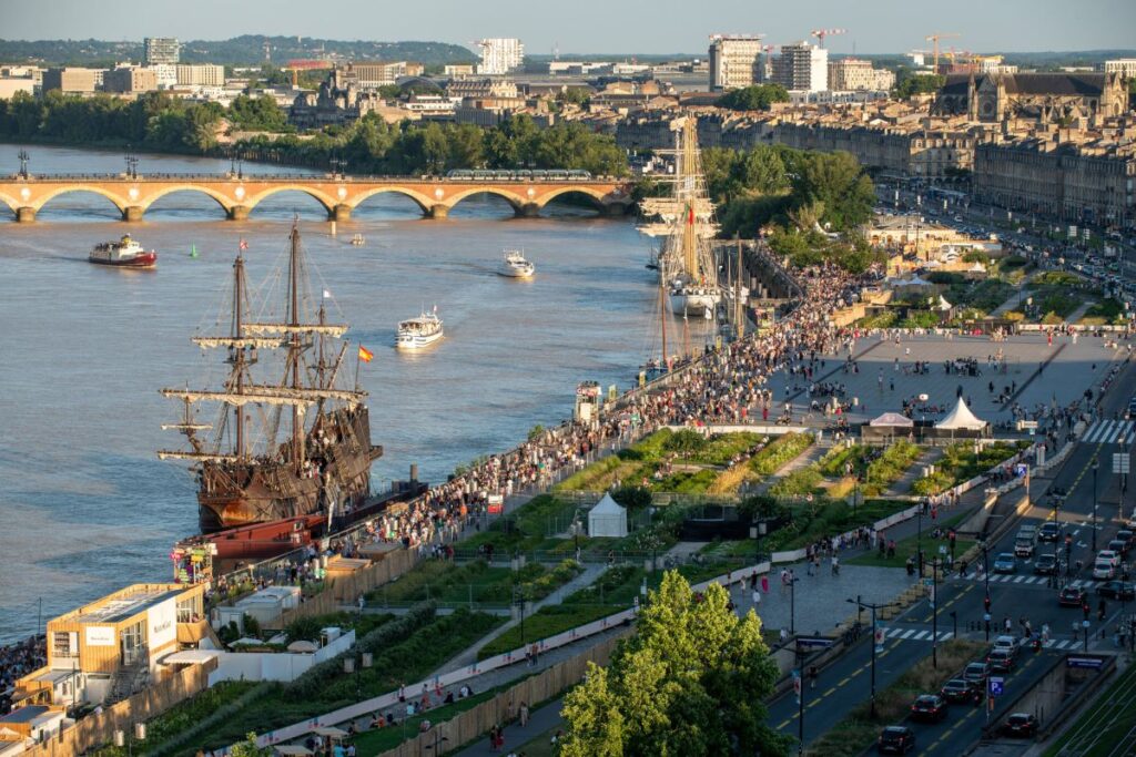 Bordeaux Fête le Vin looking down on river with tall ships and people along quayside at wine festival