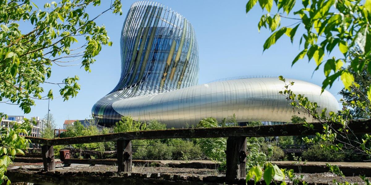 Cité du vin EXTERIOR SHOWING HUGE GLASS AND STEEL BUILDINB BEHIND A FENCE WITH CURVING TOWER