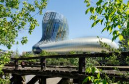 Cité du vin EXTERIOR SHOWING HUGE GLASS AND STEEL BUILDINB BEHIND A FENCE WITH CURVING TOWER