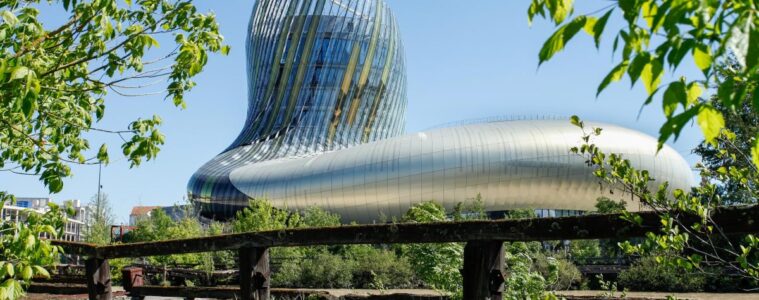 Cité du vin EXTERIOR SHOWING HUGE GLASS AND STEEL BUILDINB BEHIND A FENCE WITH CURVING TOWER
