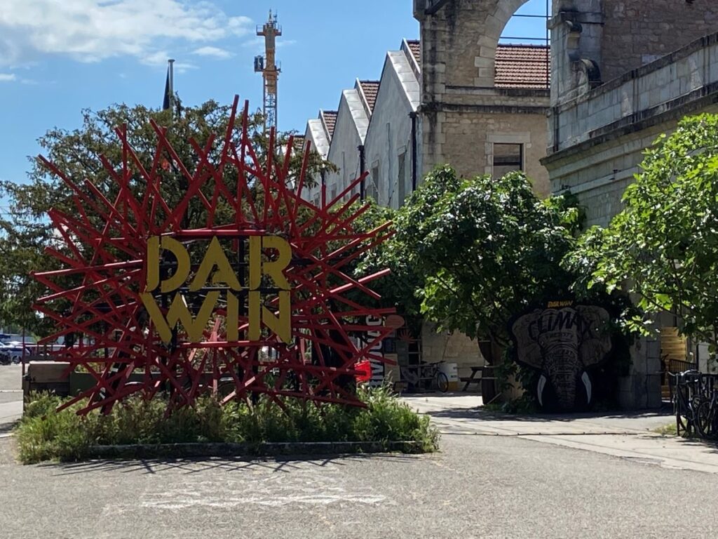 Bordeaux Darwin area sign behind bushes with old industrial buildings in the background