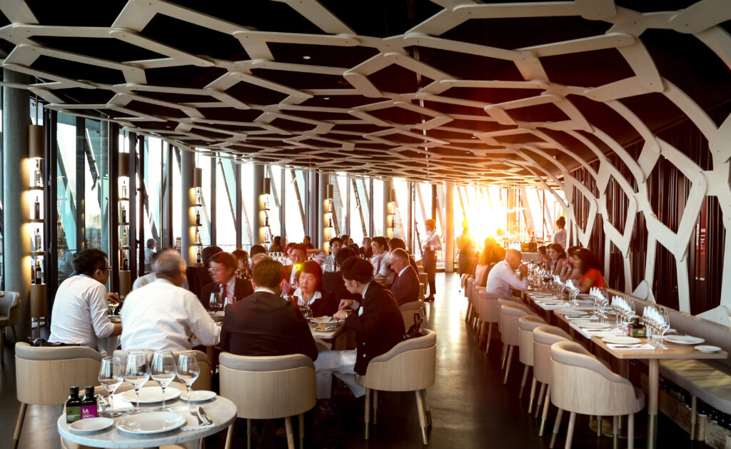 Le 7 restaurant at le cite du vin Bordeaux with curved restaurant and full tables under a honeycomb roof