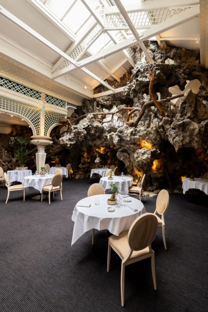 Le chapon Fin bordeaux restaurant with iron and glass roof, huge rock and vegetation