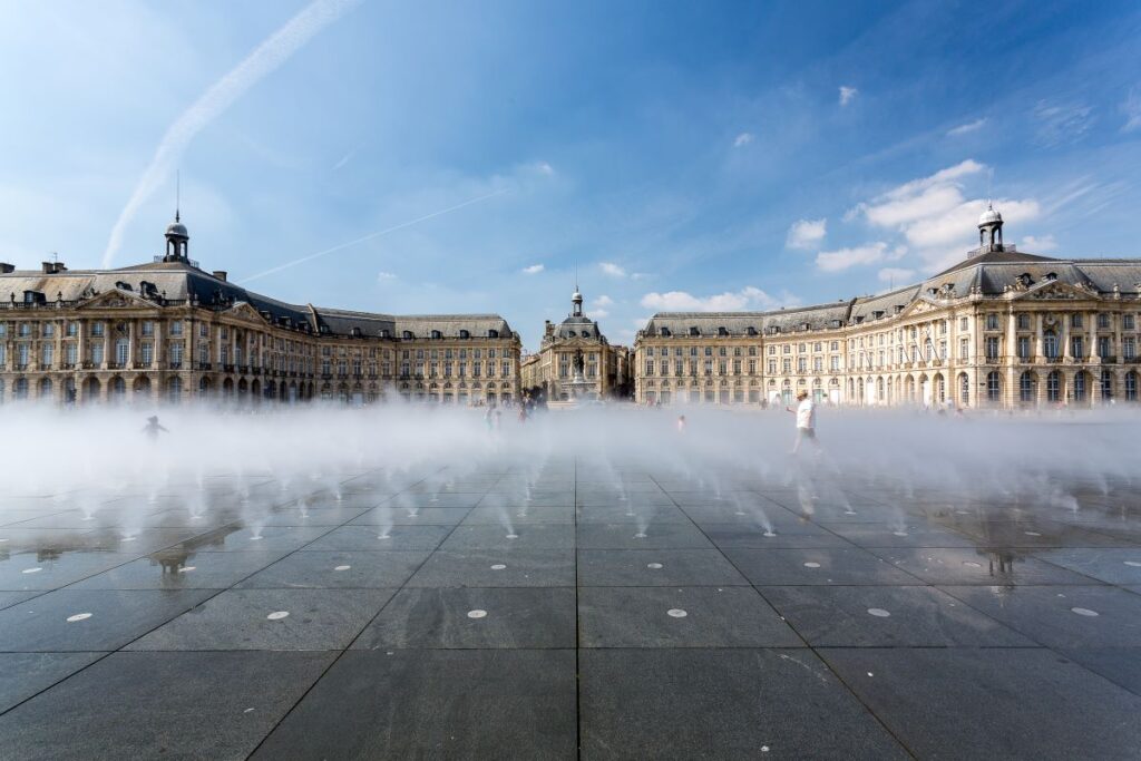 Le Miroir d'Eau in Bordeaux with classical buildings in background and misty fountains in front