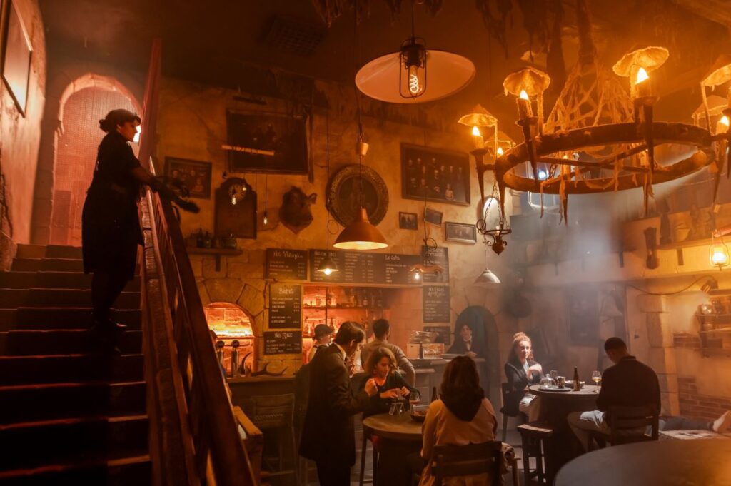 Parc Asterix - Wild Boar Bar in Halloween with dark light, woman standing looking at villainous men at tables