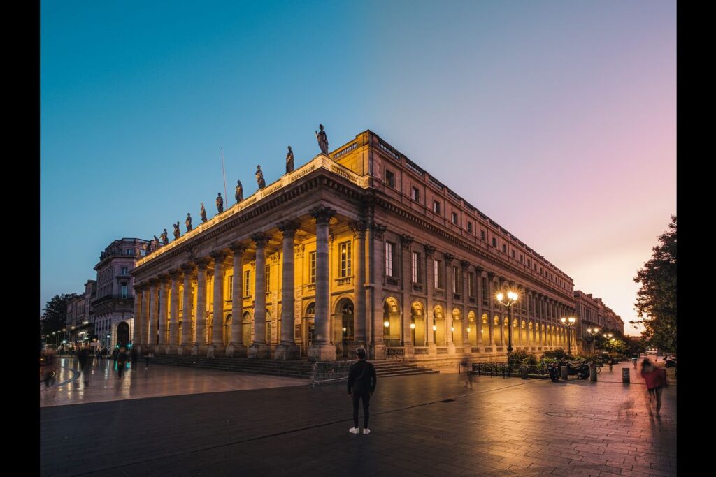 Bordeaux theatre from corner angle with yellow stone building with statues on facade at night lit up