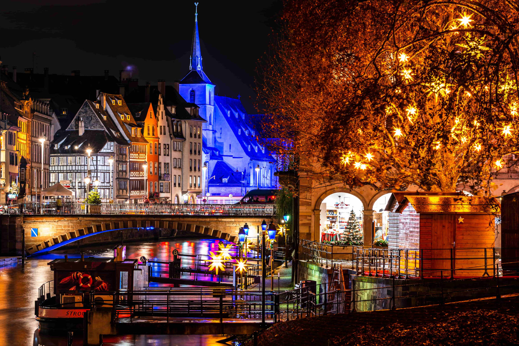 Strasbourg christmas market night with lit up trees on canal