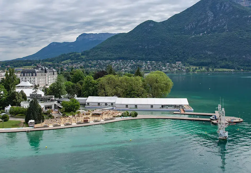 Annecy animated film festival on edges of shore with mountains and more lake in background