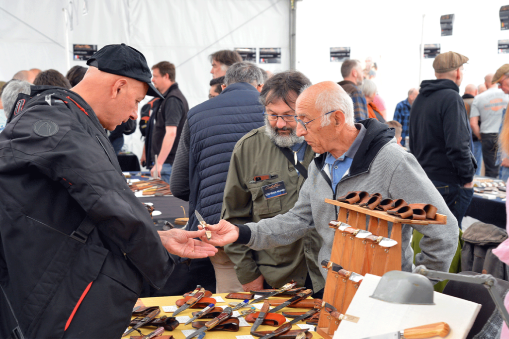 Coutellia knife festival with stall hlder showing two men knives