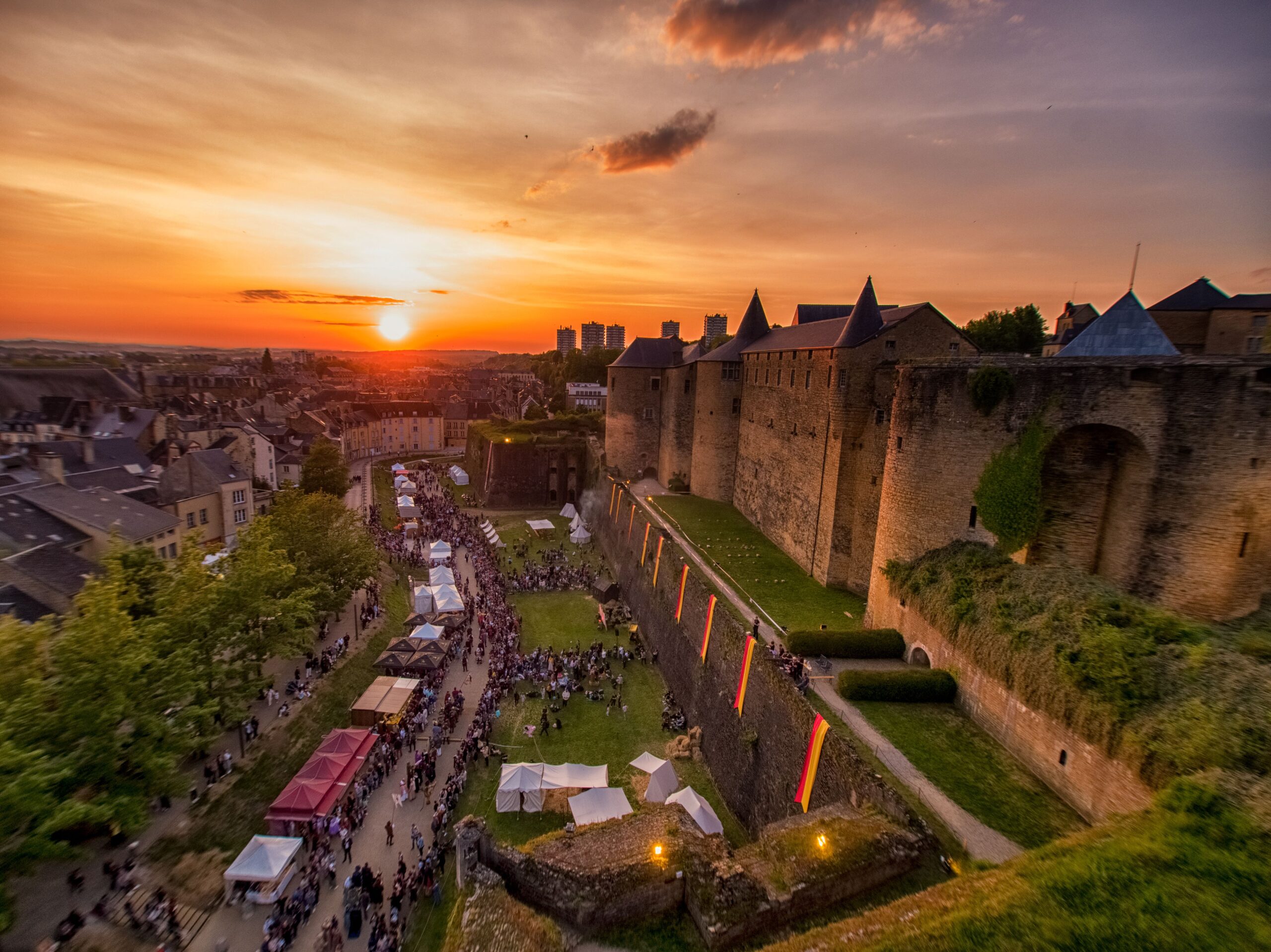 Sedan Medieval Festival at sunset looking down onto walls and moat with festival