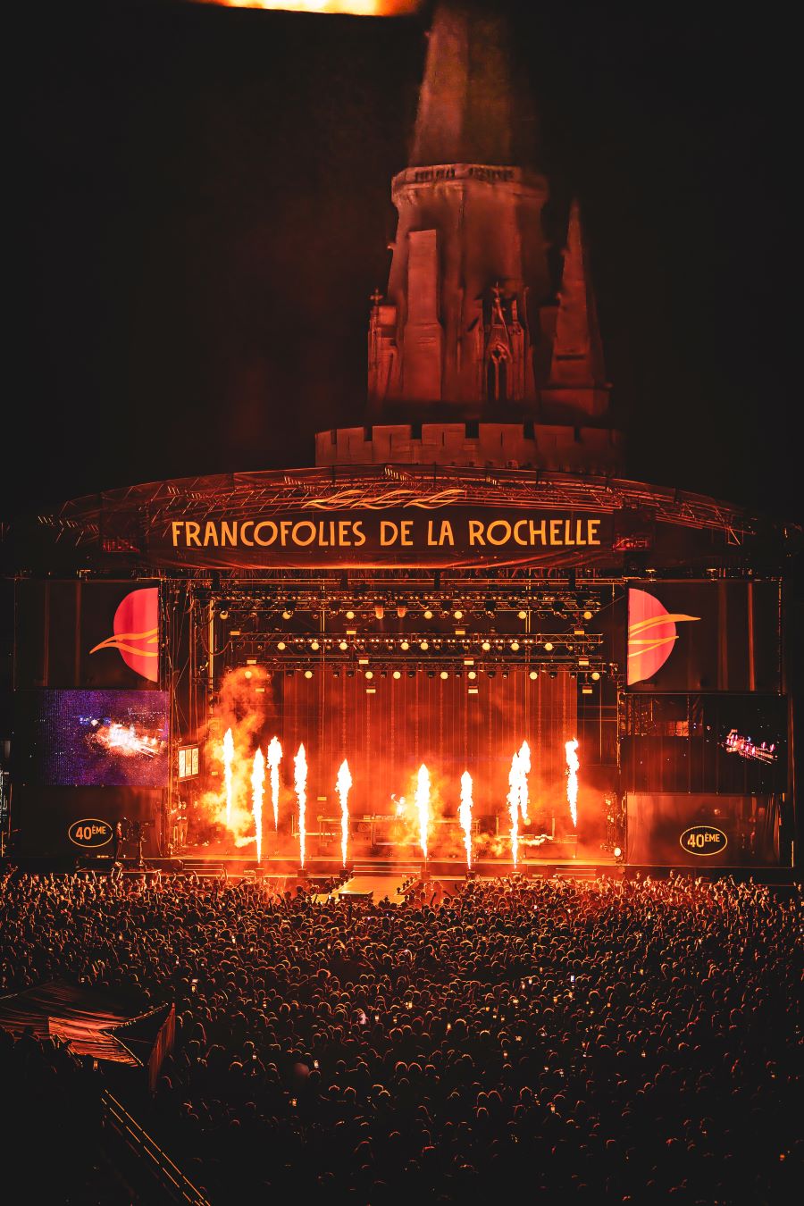 Francofolies Festival at night with flares on stage, stage behind and cathedral in background
