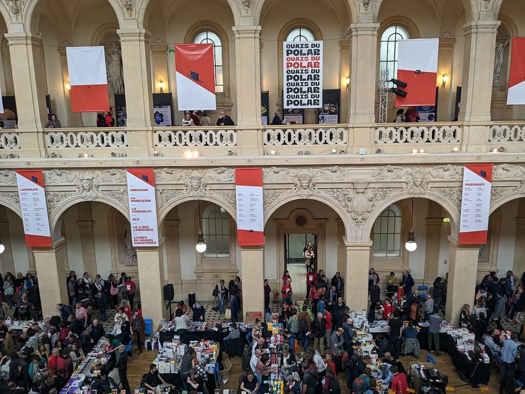 Les Quais du Polar in Palais de la Bourse Lyon looking down onto main floor with red and white banners hanging