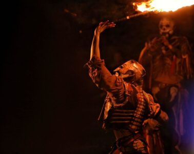 Sedan medieval fair with man at night in strange costume with fire in air