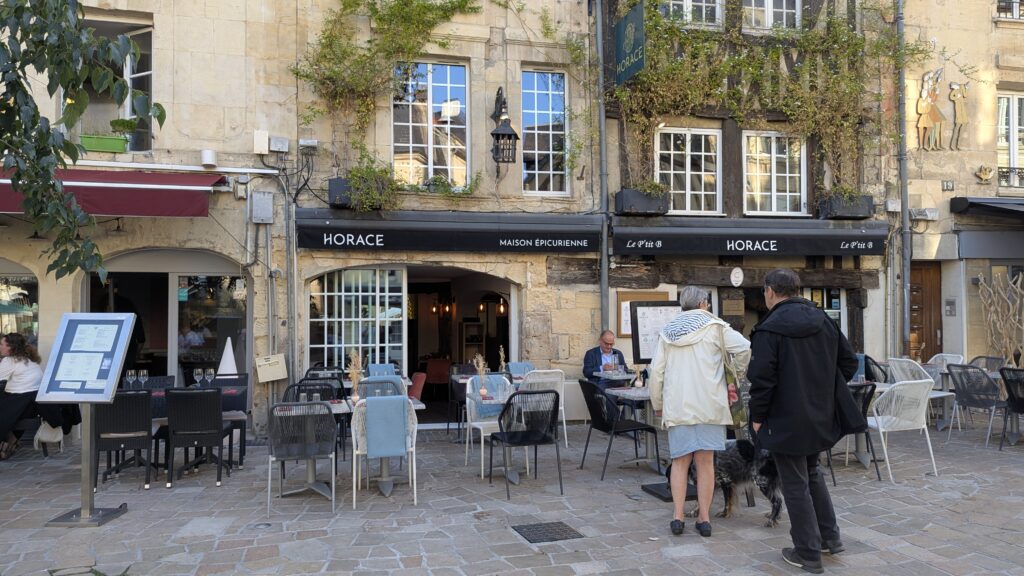 Horace restaurant Caen outside with two people approaching ivy clad stone building, tables and chairs outside