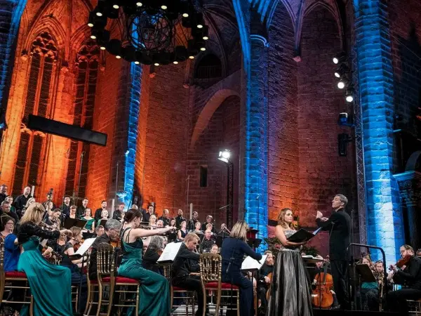 La chaise Dieu music festival in church with choir and orchestra and huge church walls and lights above