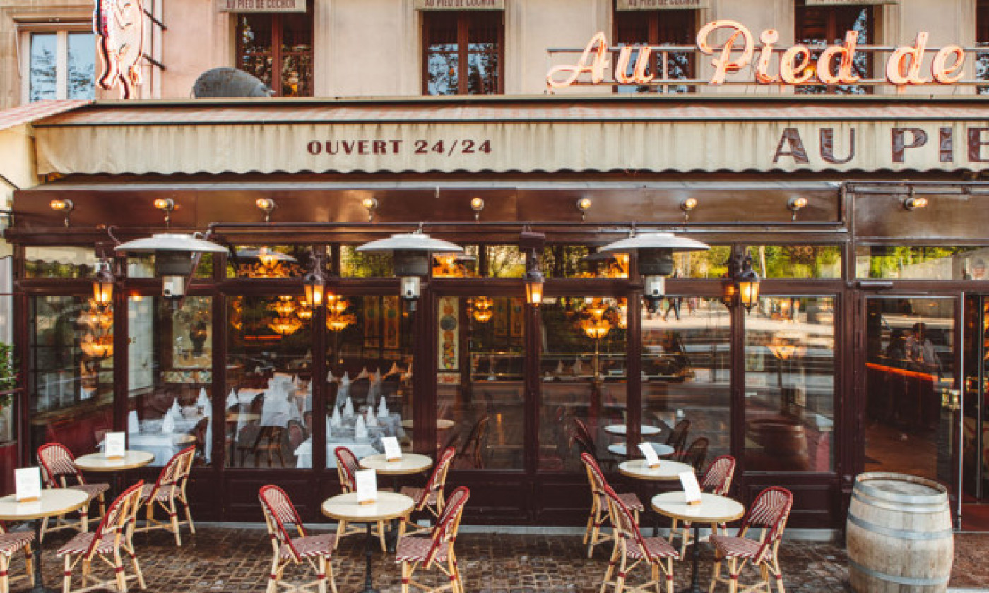 Au Pied de Cochon restaurant Paris from outside with name on awning and tables and chairs on pavement
