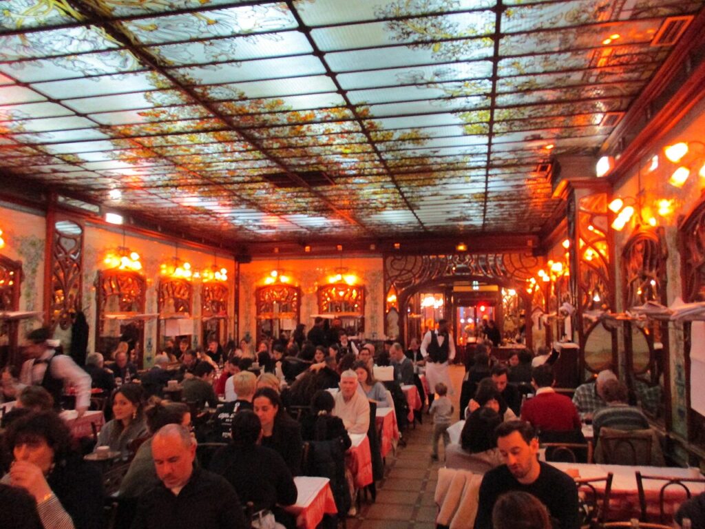 Bouoillon Chartier Montparnasse with large Art Deco room with glass ceiling, lights on walls and packed tables