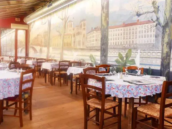 Le Carnegie hall Lyon interior with window/wall reflecting Paris and the Seine and tables and chairs with linen