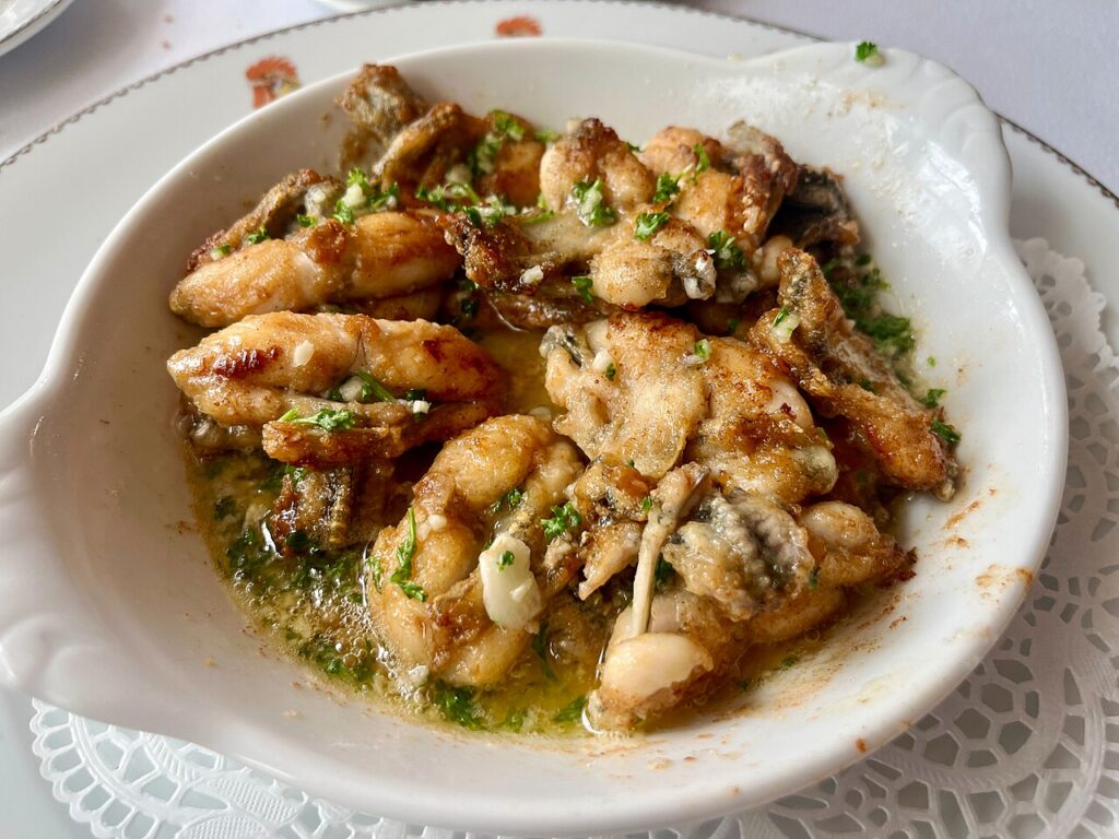Frogslegs cooking in a pan with juice , garlic and parsley