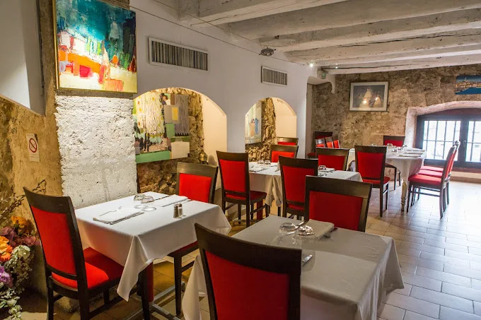 Paule et Kopa restaurant Marseille interior. Red chairs, linen on tables, white walls with paintings and arches into second room