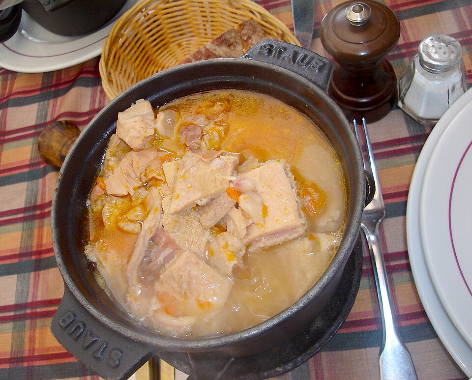 Tripe a la mode de Caen showing pot with pale yellow tripe in a sauce