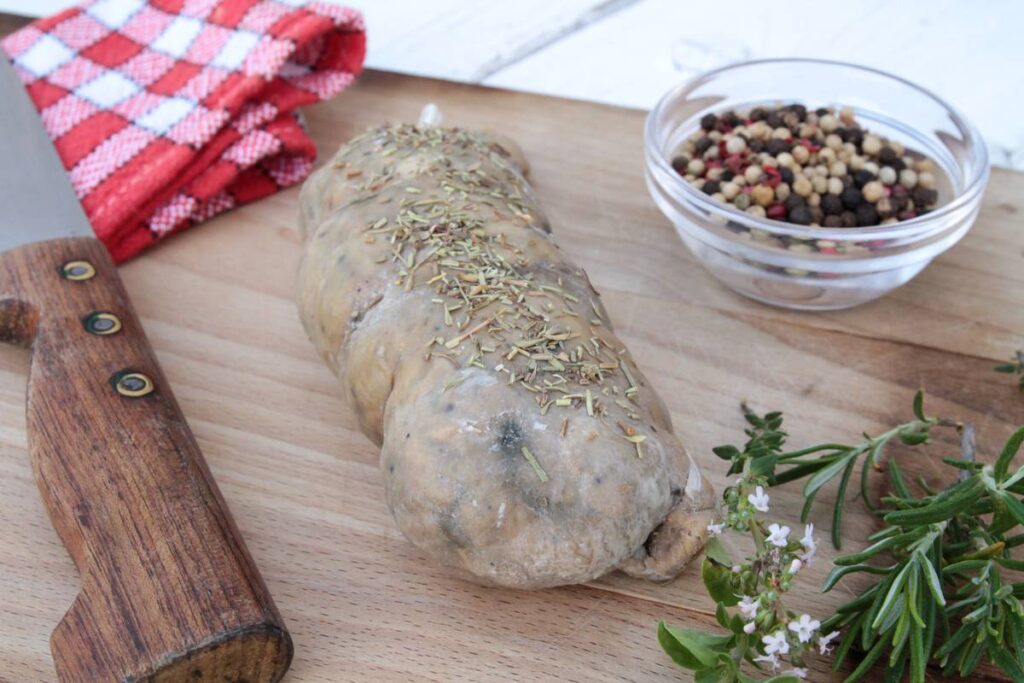 Andouillettes de Troyes with sausage on table, red gingham cloth and herbs