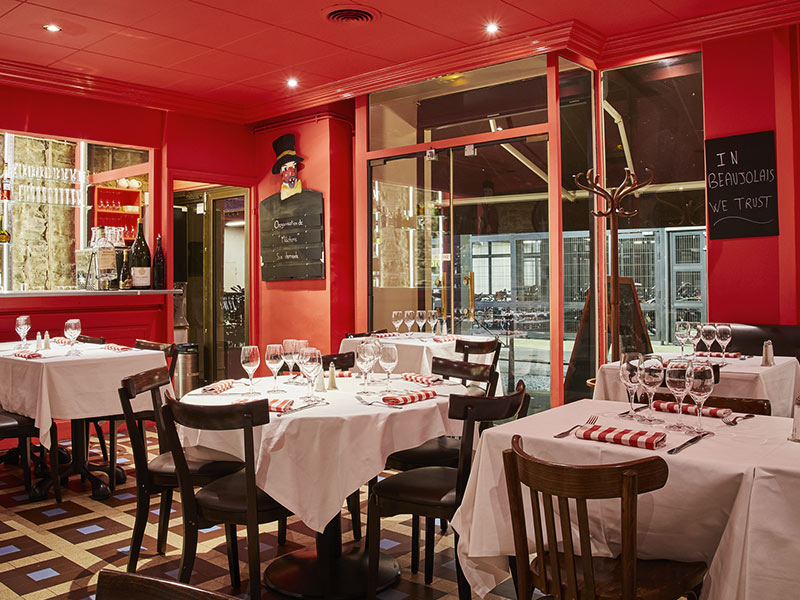 Le Bouchon des Cordeliers, Lyonwith bistro style interior with red walls, wooden tables and chairs and windows