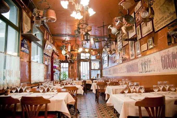 roger la Grenouille Paris large restaurant with high ceiling in brasseriestyle with smart linen covered tables, lamps and wooden floor