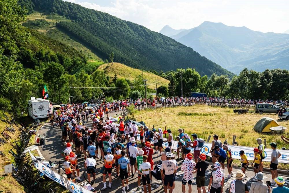 tour de France 2025 with cyclists in mountains on road with field beside