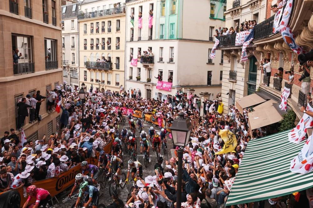 Tour de France 2025 with cyclists in packed streets in town