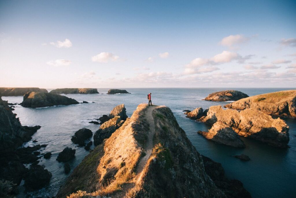 Belle Ile Brittany man on high cliff surrounded by other rocks in sea