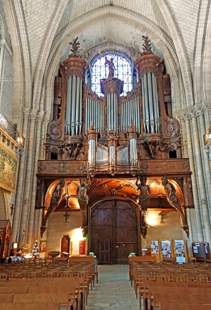 Angers cathedral organ showing huge organ with pipes and lit wall underneath